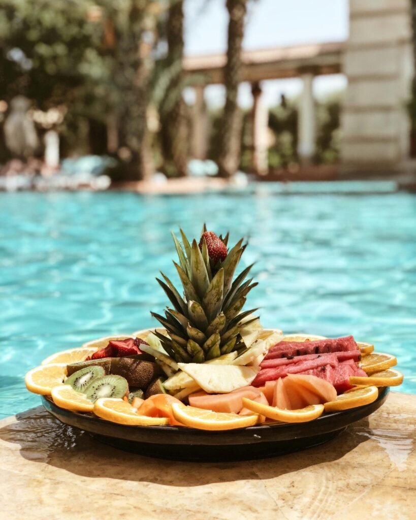 Vibrant platter of tropical fruit by a luxurious poolside in Marrakech, Morocco, perfect for a refreshing snack.